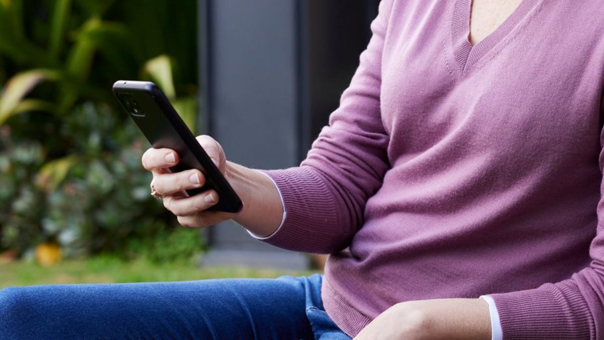 A hand leisurely holding a mobile phone outside