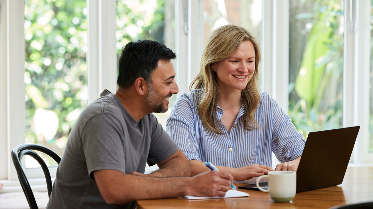 A man and a woman smiling and looking at a laptop