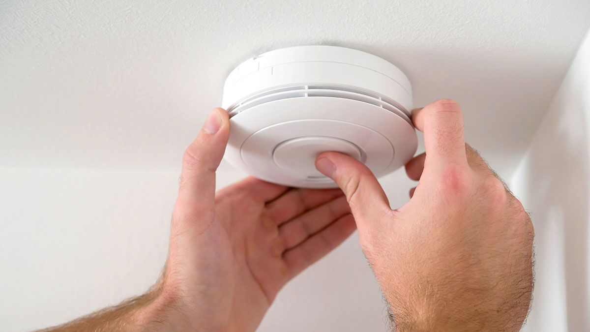 person testing smoke alarm