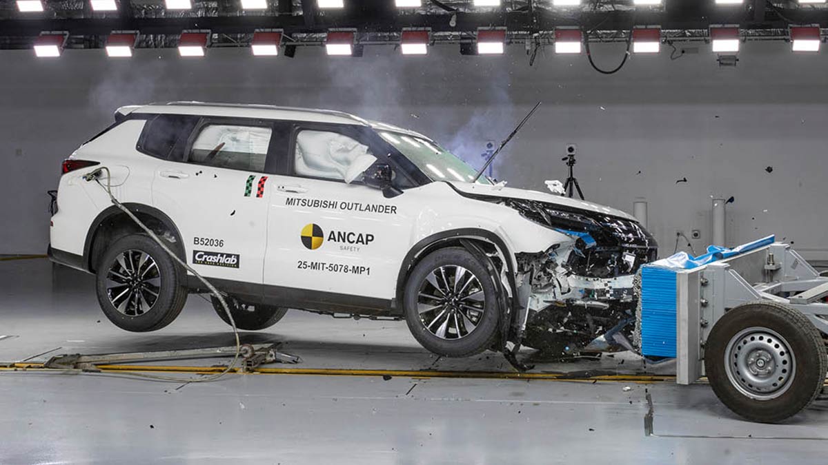 White Mitsubishi Outlander SUV crashing into deformable barrier in frontal offset ANCAP crash test.