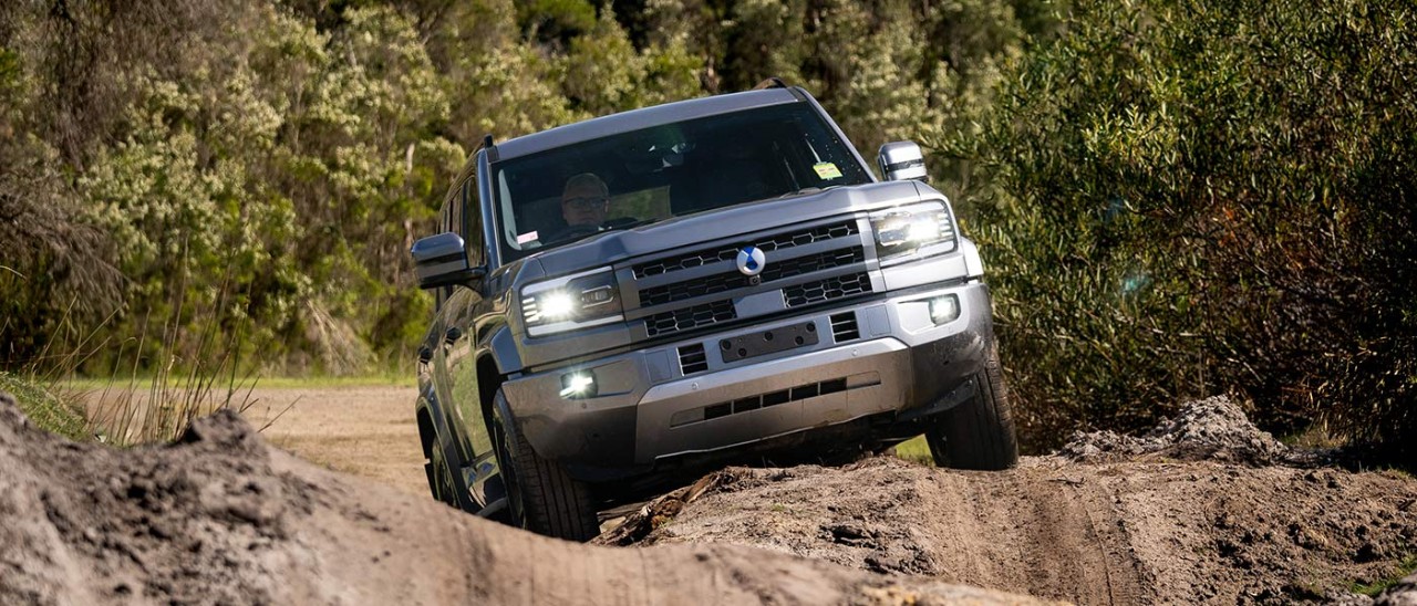 Grey Denza B5 SUV driving on steeply banked and rutted off-road course at Lang Lang proving ground in Victoria.