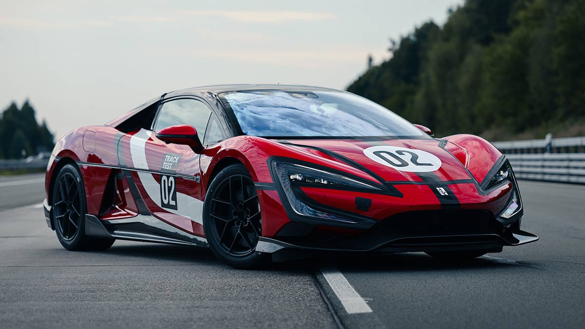Red Yangwang U9 Xtreme electric hypercar parked on tree-lined German racetrack.