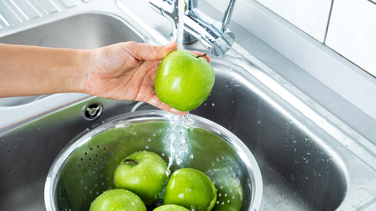 hand washing apples under running tap in sink