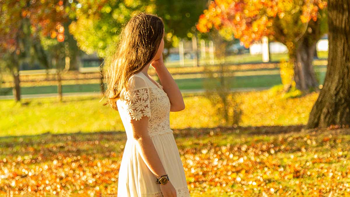 Woman walking past golden trees in autumn in Ballarat, central Victoria, Australia.