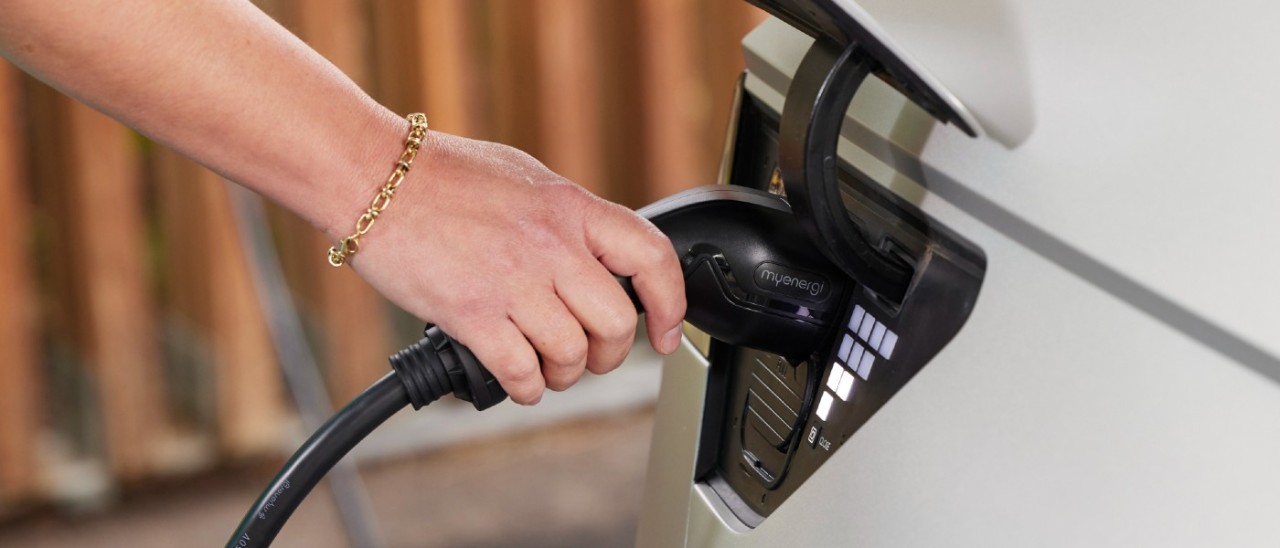 person pluggin charge cable into car