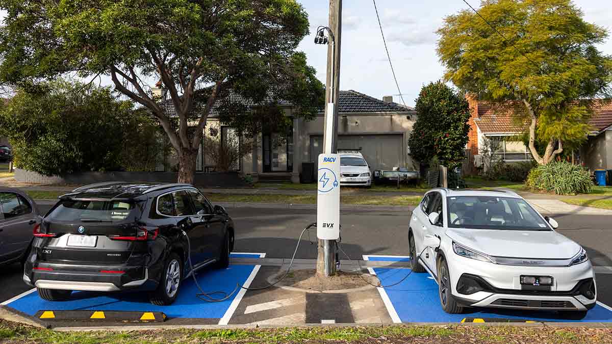 Two electric vehicles are parked at the kerb and connected to an EVX pole-mounted charger.