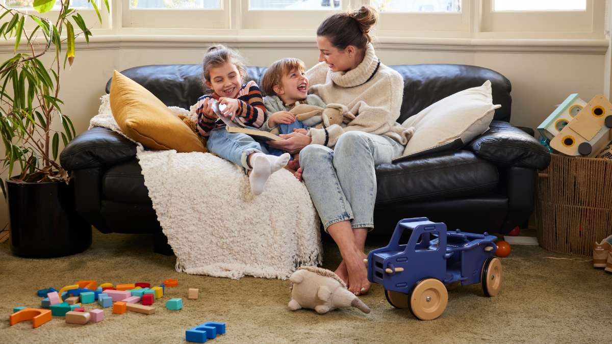 mother and two children on couch with toys strewn around
