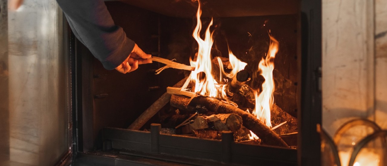 person placing a stick on an indoor fireplace