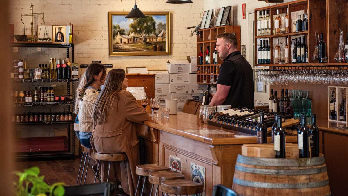 two women enjoying a wine tasting served by a man