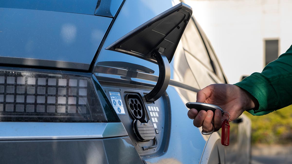 Hand on remote control opening EV charging flap of blue Hyundai Ioniq 5