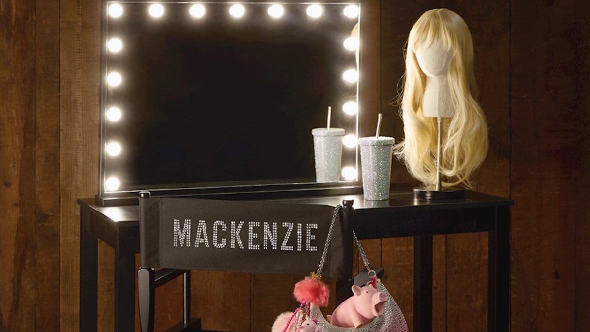 dressing table with sparkly drink cup, blonde wig and pink bag with a pig squeaky toy