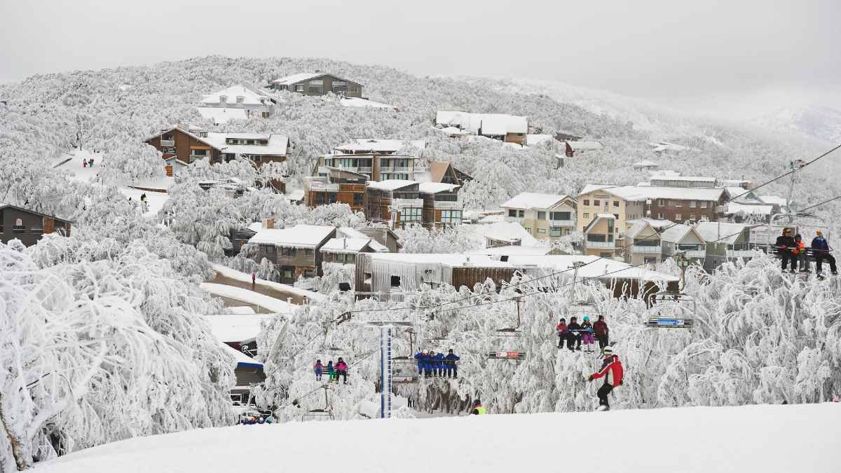 skiier on slopes under chair lift at Mt Buller, Victoria with ski village in background