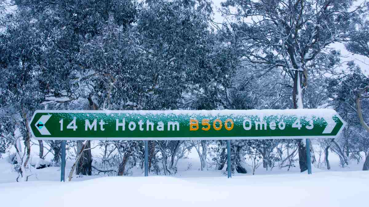 snowy road sign displaying directions to Mt Hotham and Omeo
