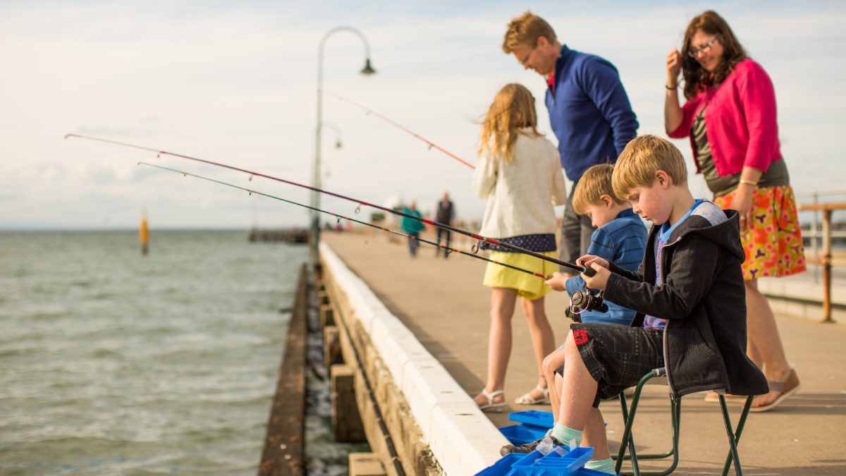 family fishing off an ocean pier