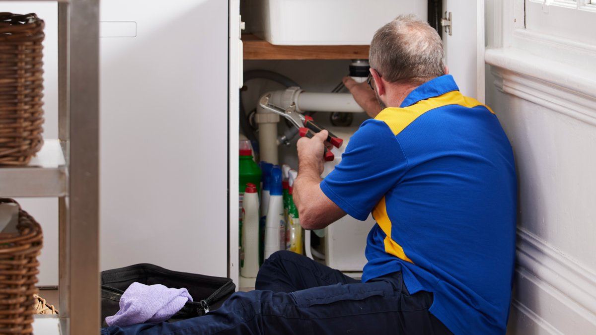 RACV plumber fixing pipe under kitchen sink