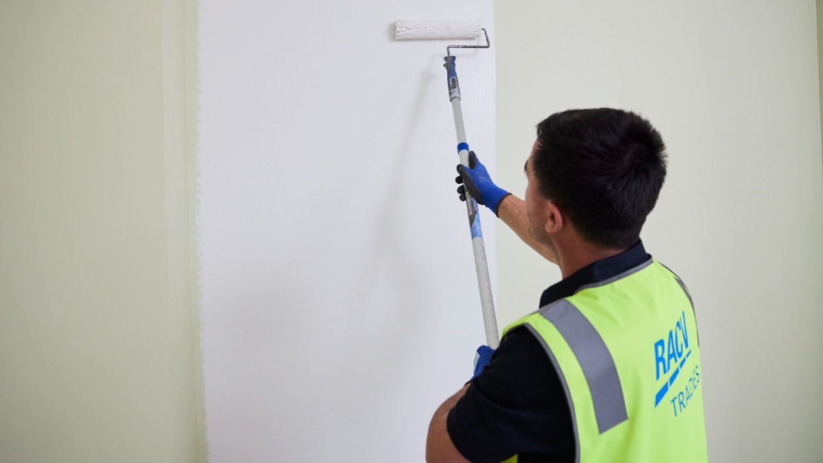 person removing leaves from gutters on roof