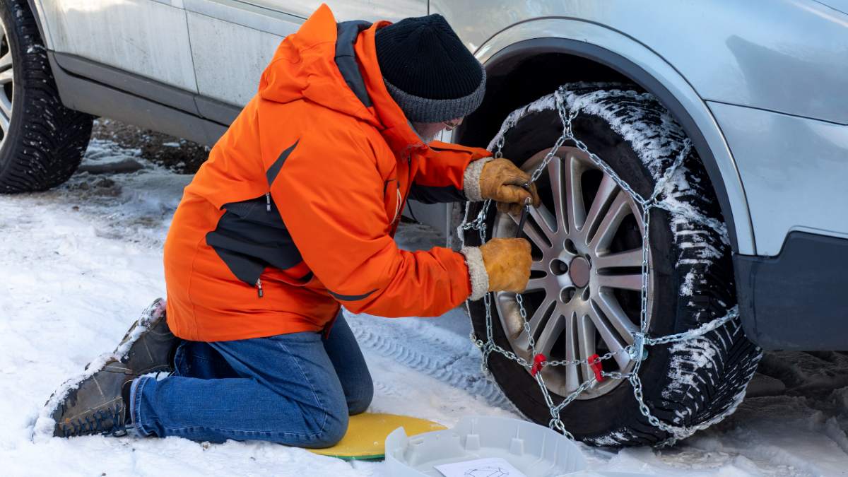 A car wheel covered with snow chains.