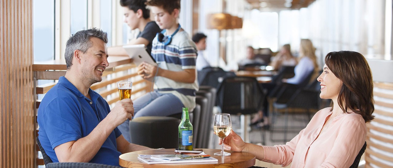Couple enjoying drink in lounge area while sons play on devices