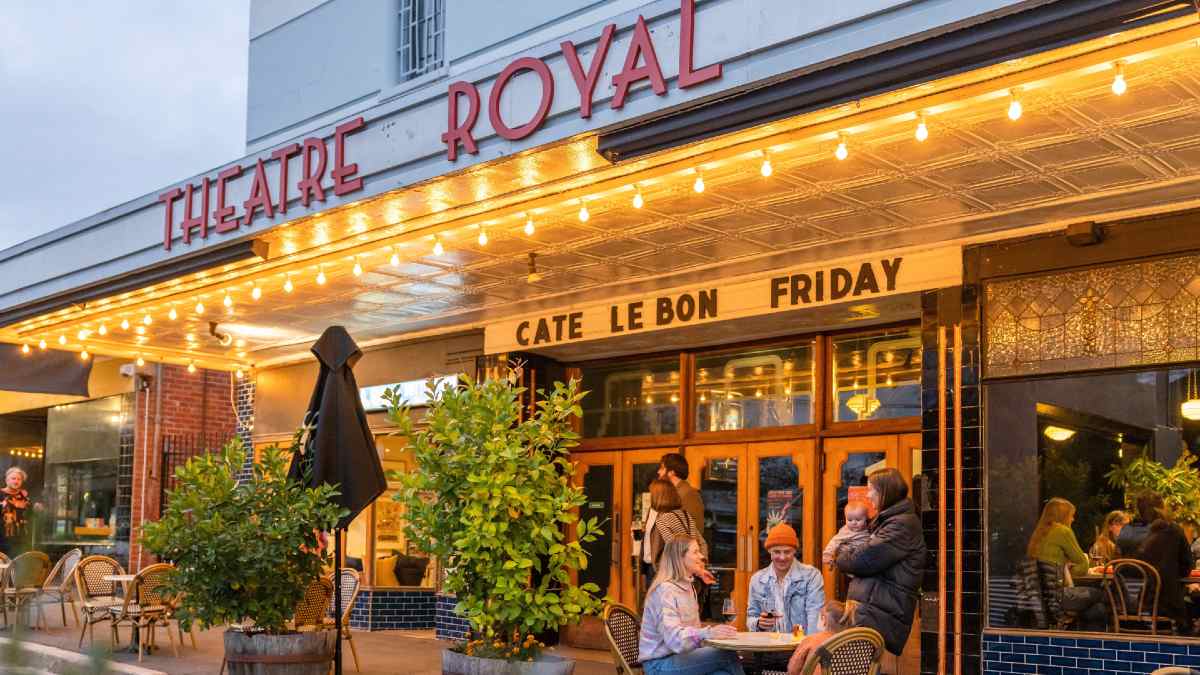 people sitting outside a brightly-lit theatre