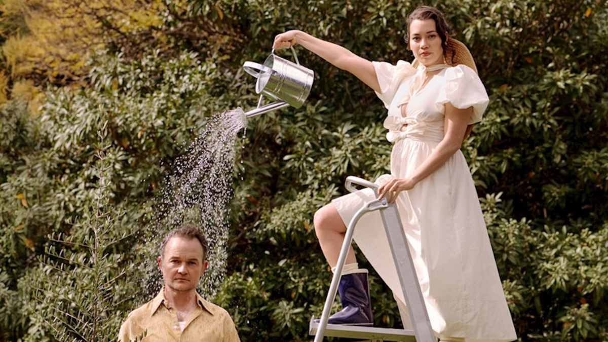 young woman pouring water on an older man from a watering can