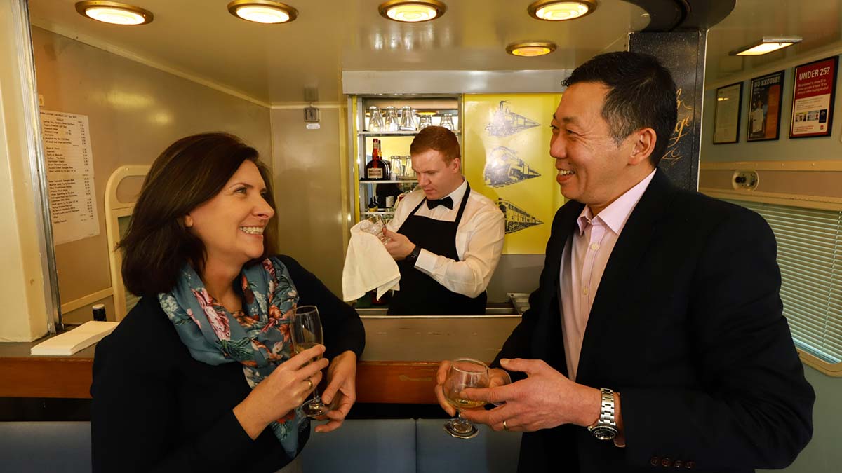 A couple enjoy a drink in the lounge carriage on the Vintage Rail Journeys