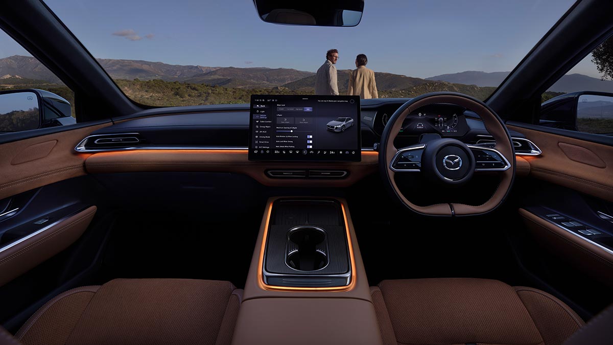 Cockpit of Mazda 6e with minimal layout, tan leather trim, orange ambient lighting and large central screen.