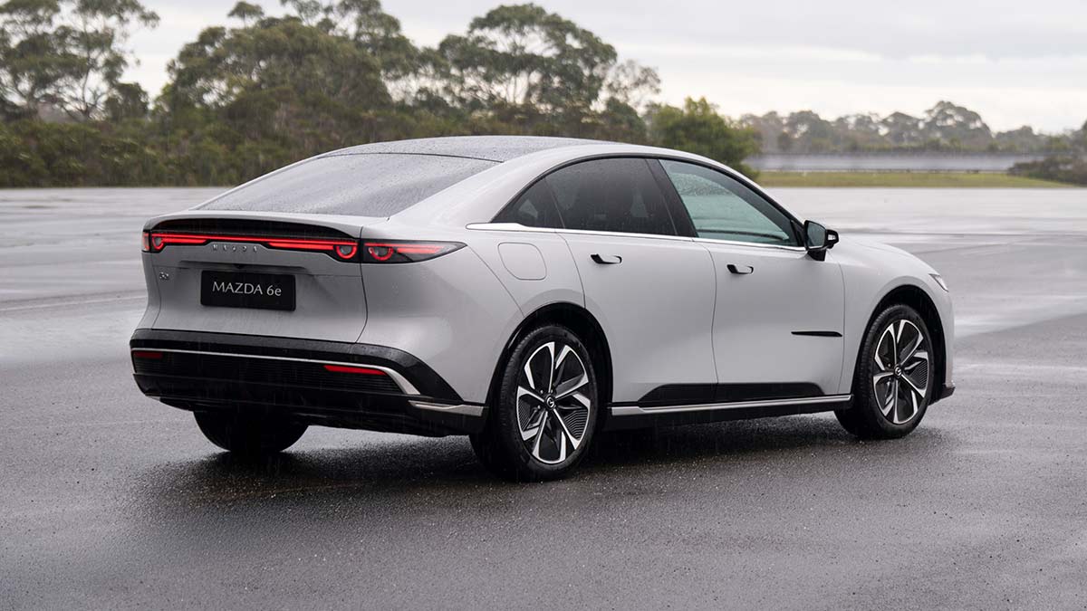 Rear view of light grey LHD Euro-spec Mazda 6e sedan on wet bitumen forecourt at Lang Lang proving ground in Victoria.