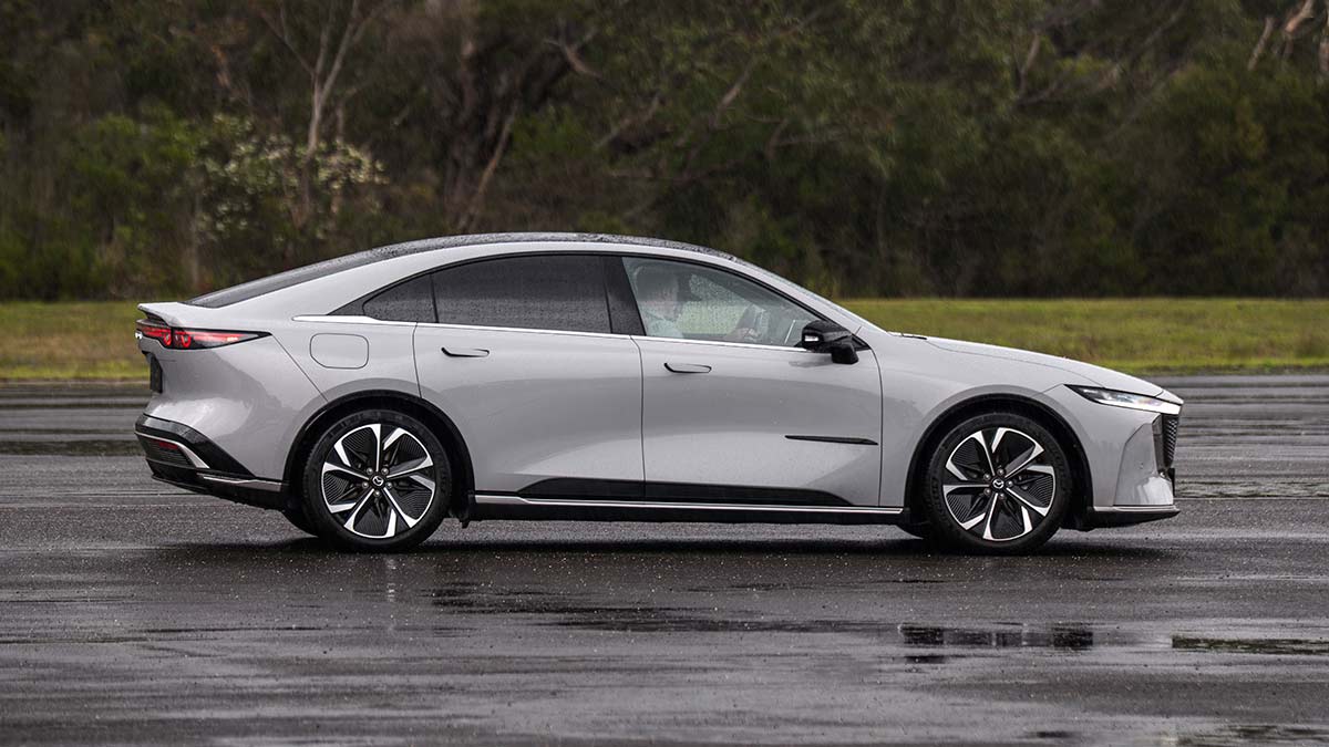 Side view of light grey LHD Euro-spec Mazda 6e sedan on wet bitumen forecourt at Lang Lang proving ground in Victoria.