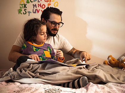Father and child reading a book in cosy bedroom