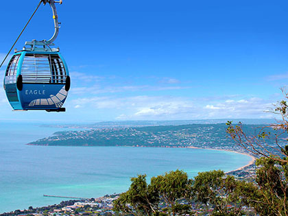 Gondola travelling over Arthur's Seat, mountains and coast in the background.
