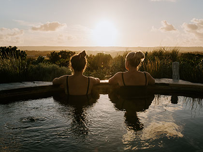 Two women looking over the edge of an outdoor bath at the peninsula landscape.