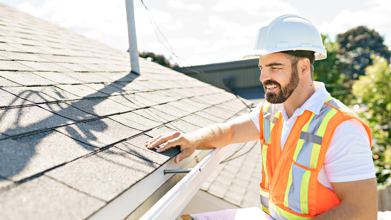 Man in a hardhat and high-vis vest inspecting a house during a building inspection.