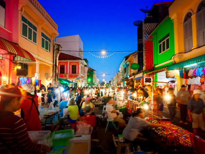 Busy night market surrounded by colourful buildings.