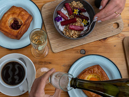 Bird's eye view of cafe breakfast, including danishes, granola and coffee.