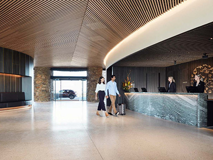 A couple walk up to reception in the stunningly architected lobby of RACV Cape Schanck Resort