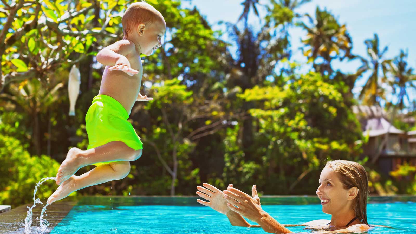 A mother and child playing in a pool on a sunny day in Bali.