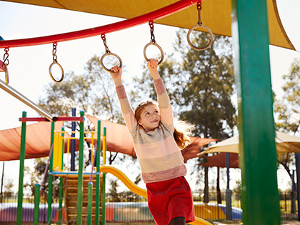 Child swinging from monkey bars at RACV Cobram Resort's playground.