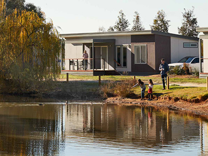 Family with children playing by lake next to cabins at RACV Cobram Resort.