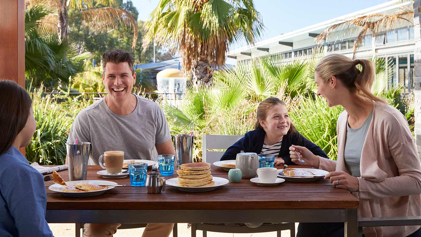 Family eating at outdoor table at poolside cafe at RACV Cobram Resort.