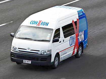 Con-X-Ion shuttle bus driving down a road.