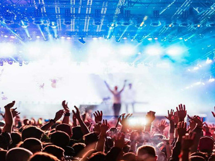 A large crowd at a concert with bright blue lights.