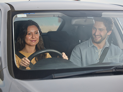 Couple in a car driving and smiling.