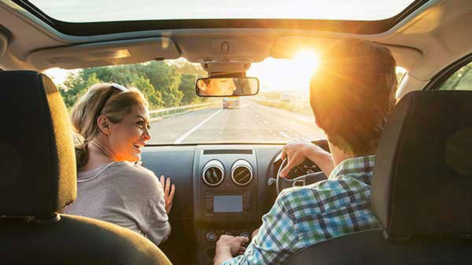 The view from the backseat of a young couple driving.