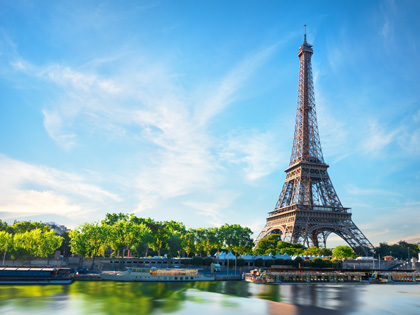 Eiffel Tower with a blue sky in the background and the river Seine in the foreground