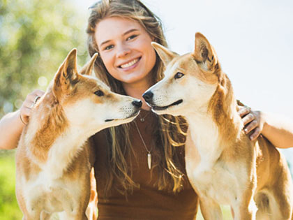 Girl posing with two dingoes at Moonlit Wildlife Sanctuary.