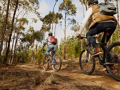 Two people riding bikes on a mountain bike trail near RACV Goldfields Resorts.