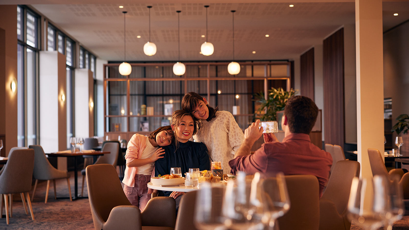 Person taking a photo of their partner and two kids at RACV Healesville Country Club & Resort's Banyalla restaurant.