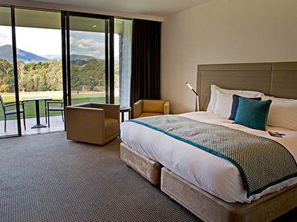 Room at RACV Healesville Country Club & Resort, featuring a large bed, desk, couches and outdoor area with mountain view.