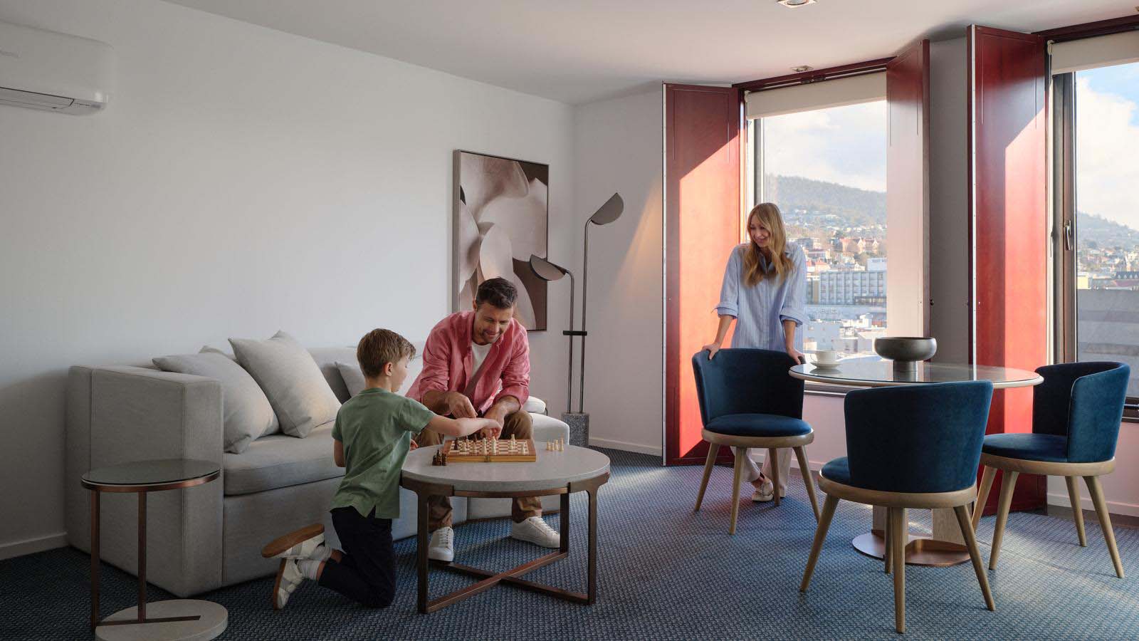 A father and son playing chess in the living area of their room at Hobart Hotel.