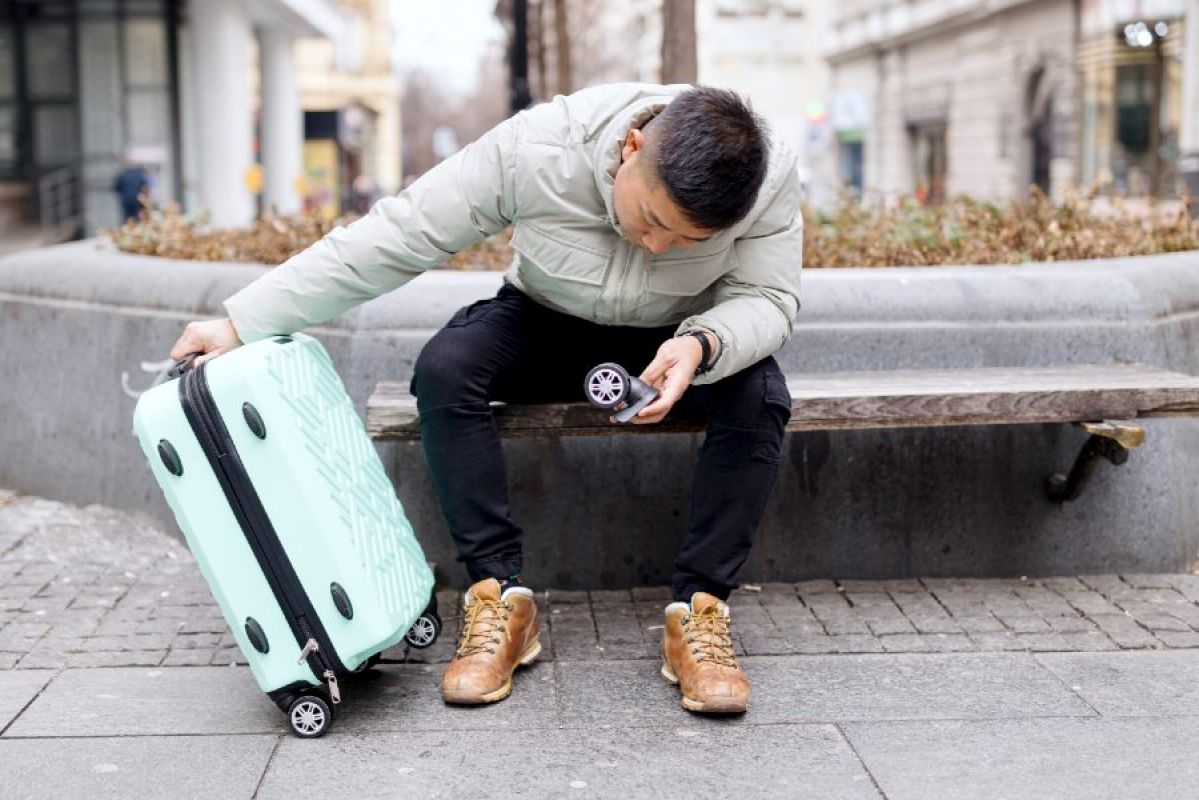 young man looking at damaged suitcase
